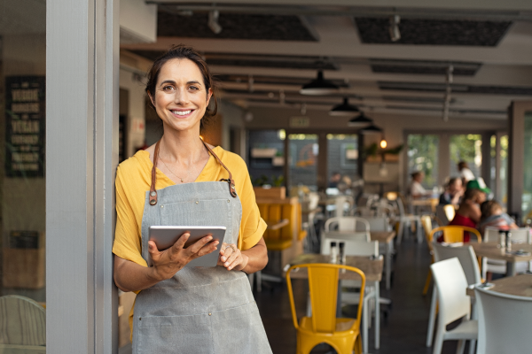 Smiling Connecticut restaurant owner holding tablet computer