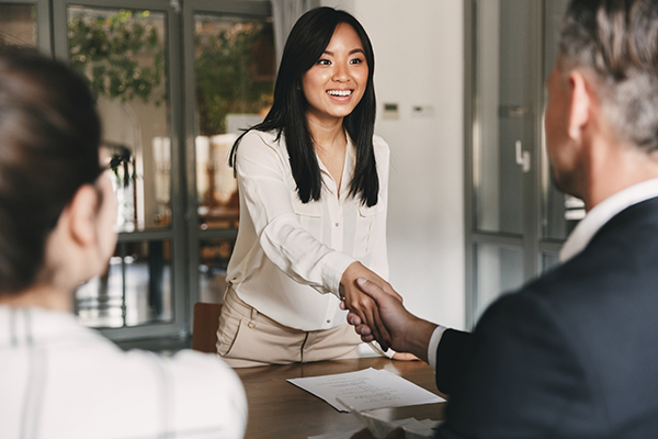 Woman in an interview shaking hands with hiring team.